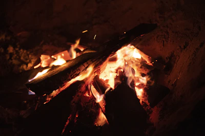 Close-up of a campfire glowing warmly under a mustard yellow sunset sky.