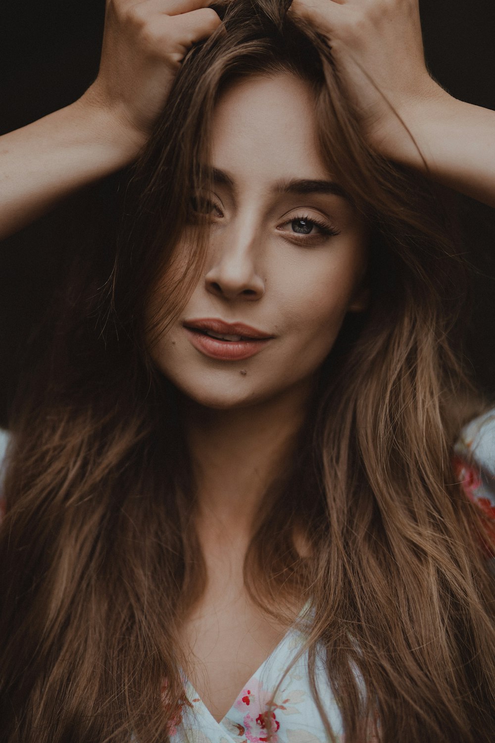 a woman with long brown hair is holding her hands on her head