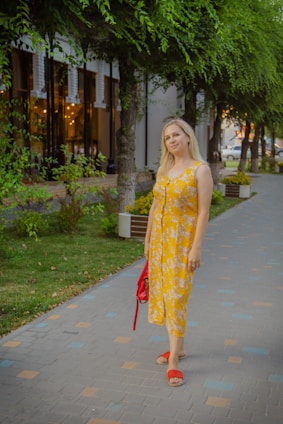 A woman in a chic dress holding a shopping bag, standing in a bright urban setting