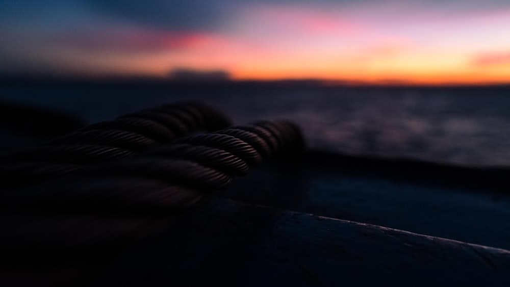 Schwarzes Seil auf schwarzer Holzoberfläche bei Sonnenuntergang