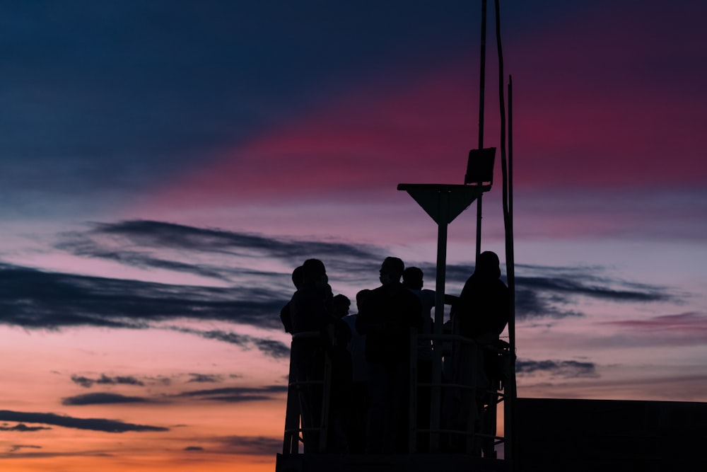 silhouette of people standing on ship during sunset