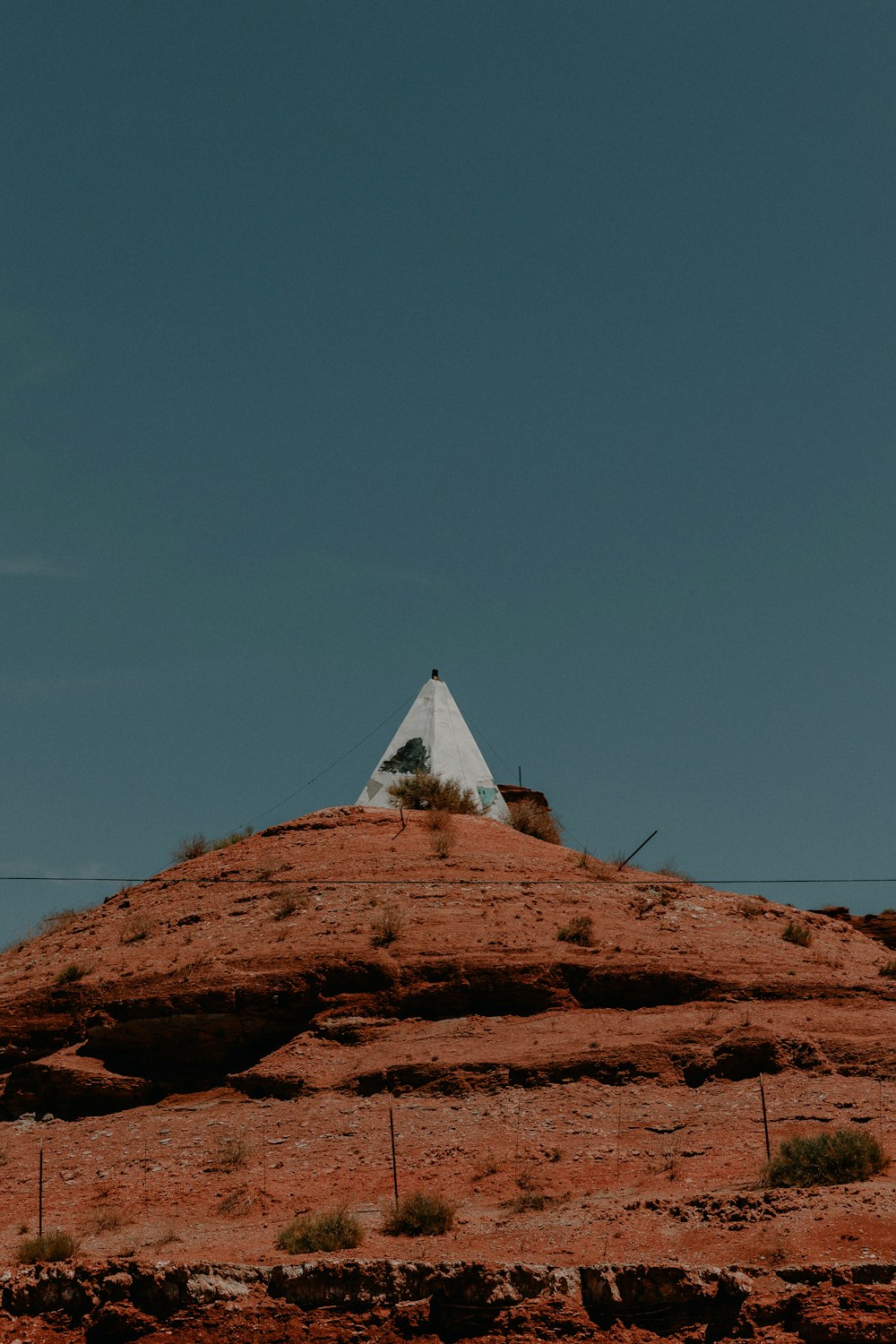 white tent on brown rock formation under blue sky during daytime