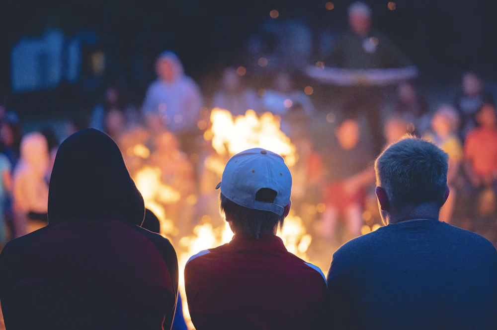 A camp leader briefing a group of young people in the evening