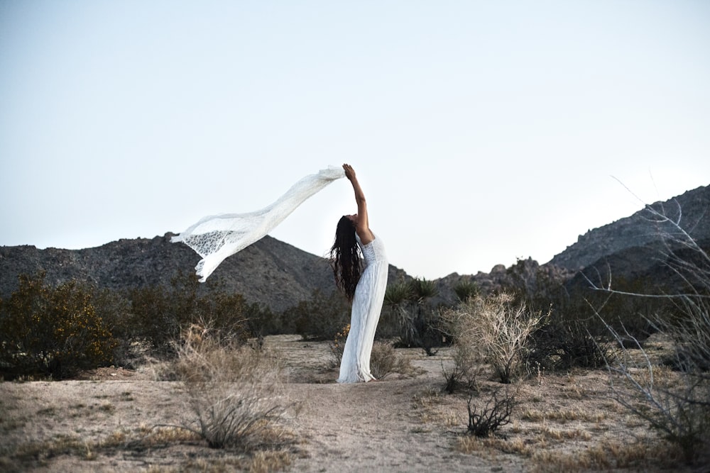 woman in white dress standing on brown grass field during daytime