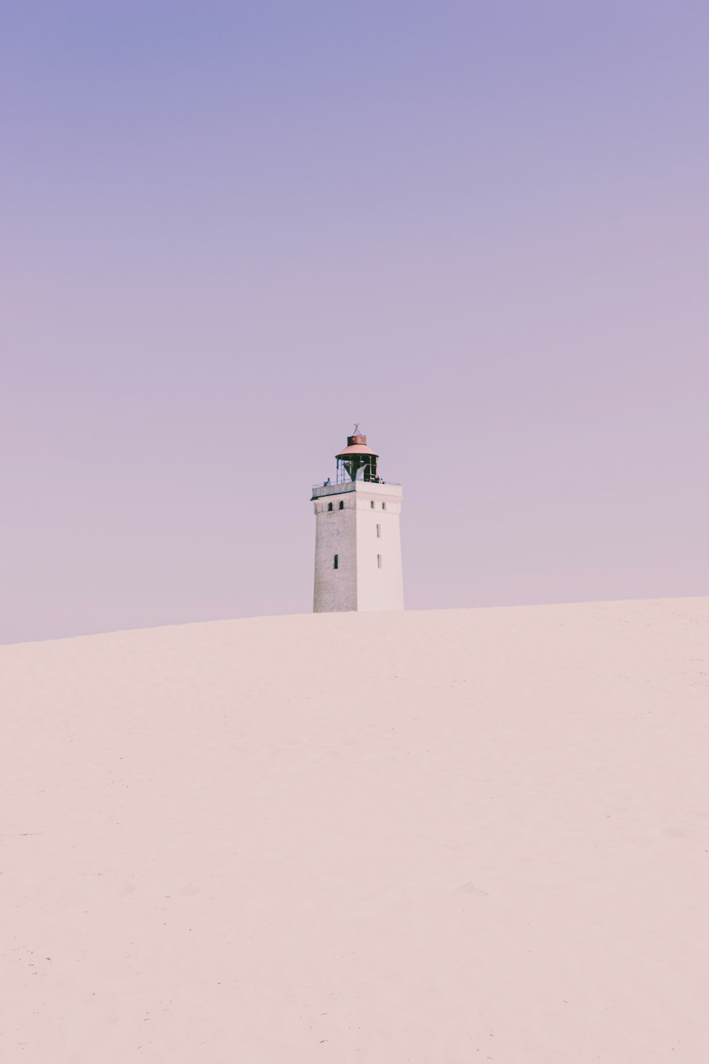 white concrete lighthouse on white sand during daytime