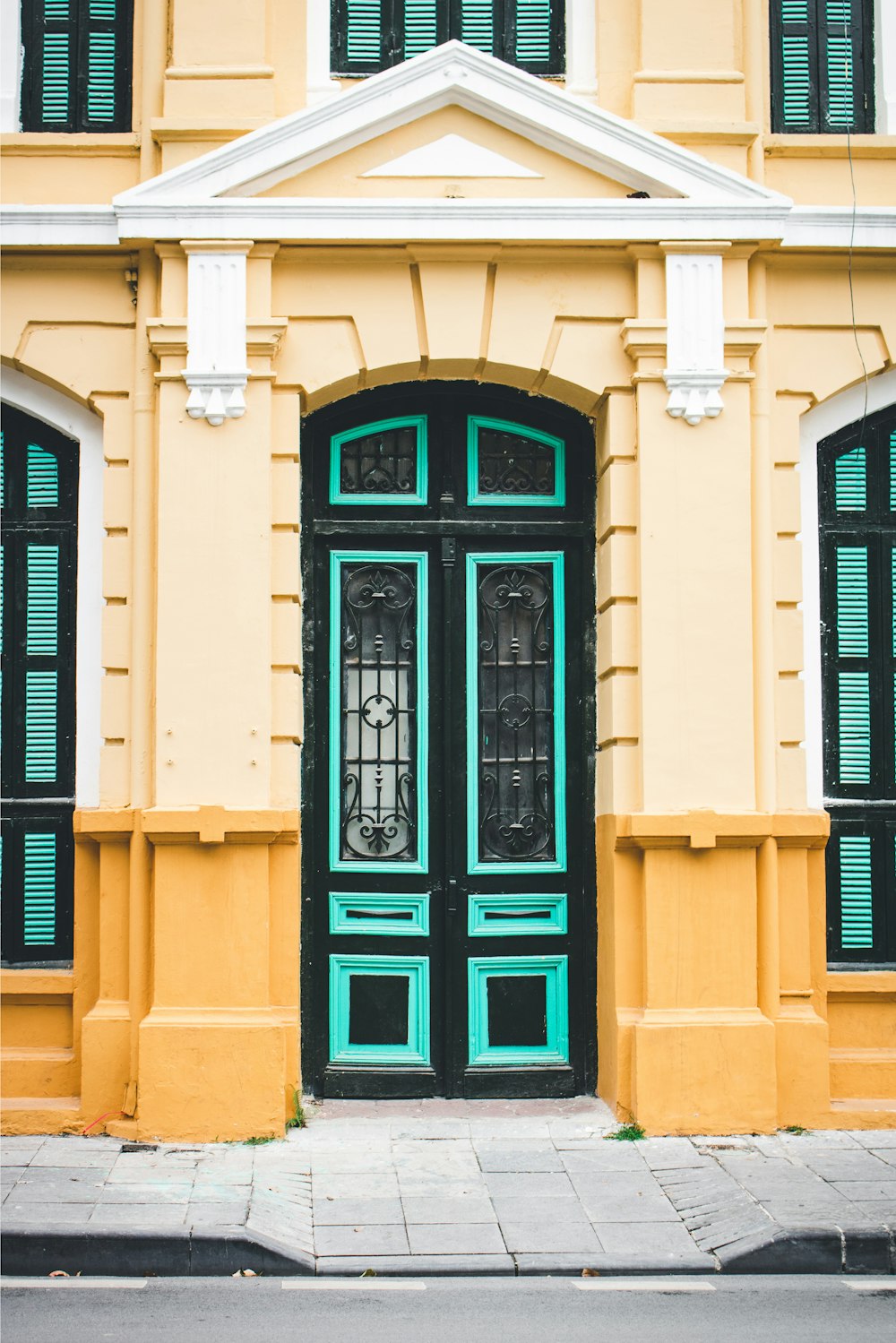 a yellow and green building with a black door