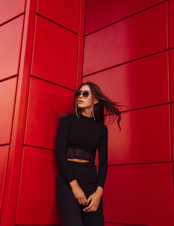 A stylish woman leaning against a colorful wall, embodying confidence and warmth.