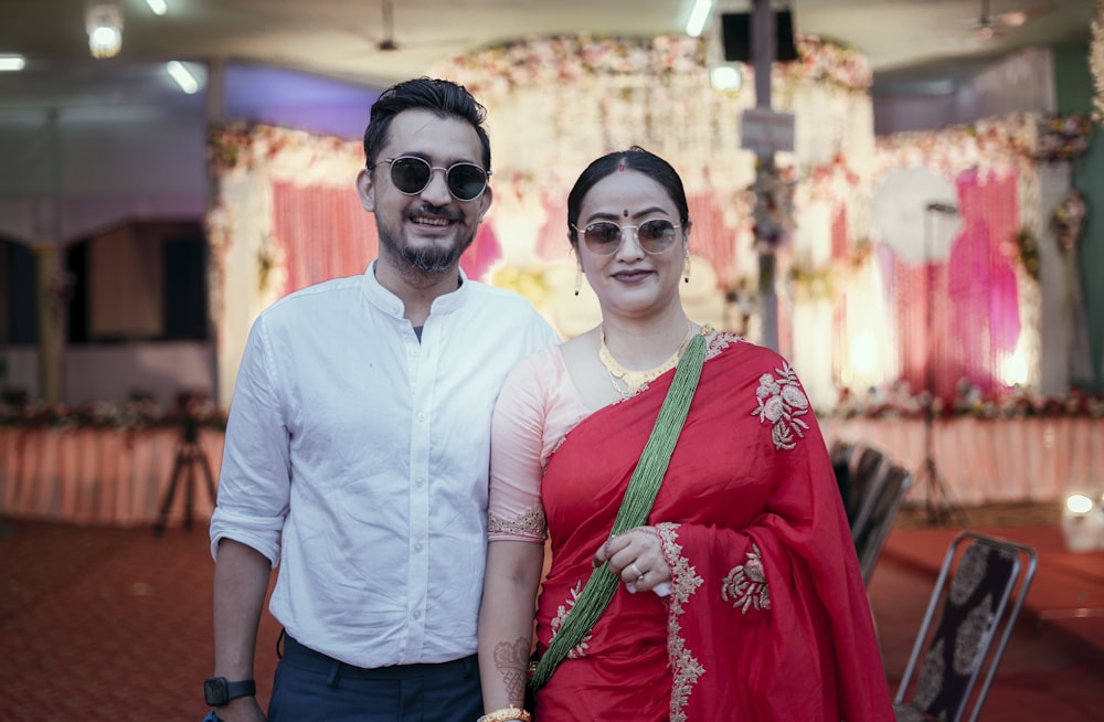 man in white crew neck t-shirt beside woman in green and red sari