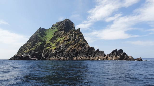 green and brown mountain beside body of water during daytime