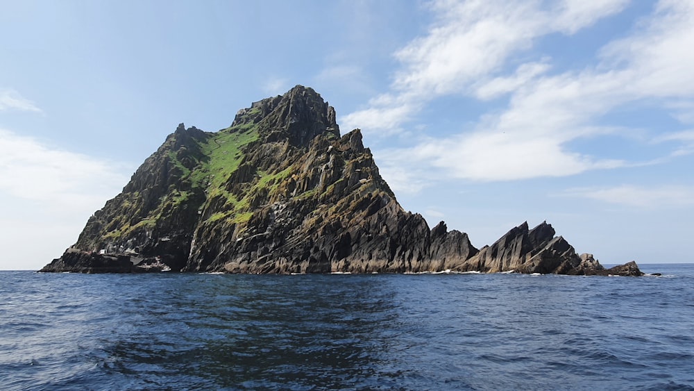 green and brown mountain beside body of water during daytime