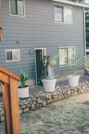 A welcoming realtor shaking hands with a happy couple in front of a modern luxury home.