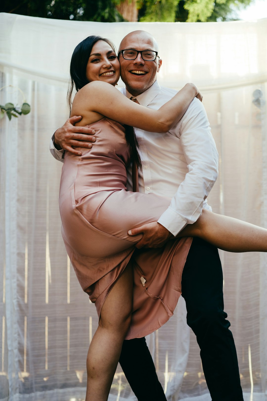 woman in white long sleeve shirt hugging woman in brown sleeveless dress