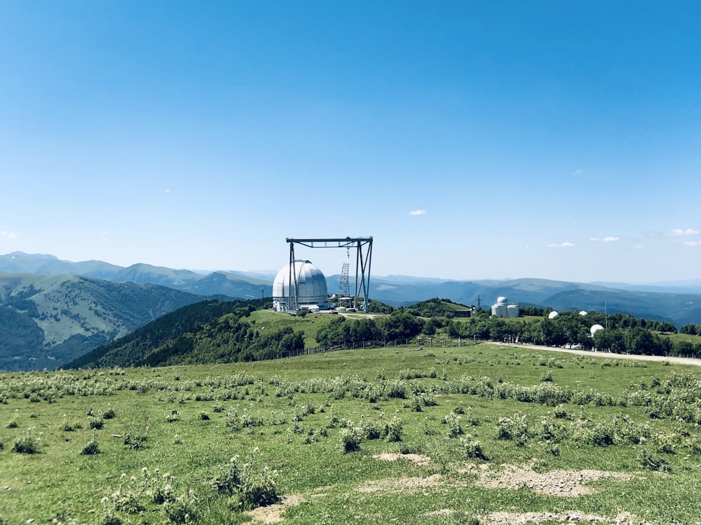 green grass field near green mountains under blue sky during daytime