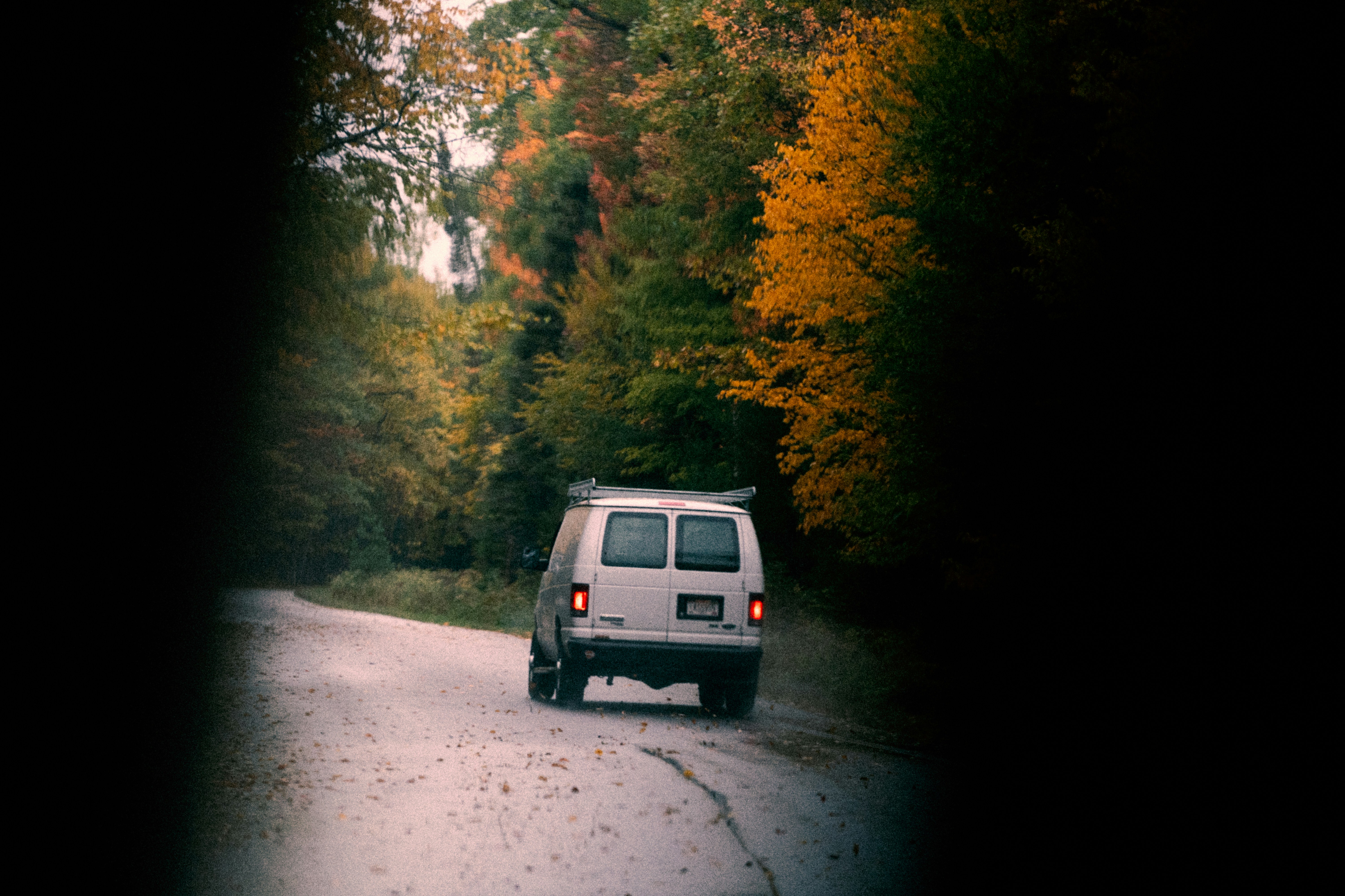 black suv on road between trees during daytime