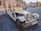 A vintage-style convertible car is parked on a cobblestone street in a historical area. The car is decorated with a sign offering sightseeing tours for 50 euros or 1200 CZK. There are buildings with classic architecture in the background along with a few pedestrians and parked cars.