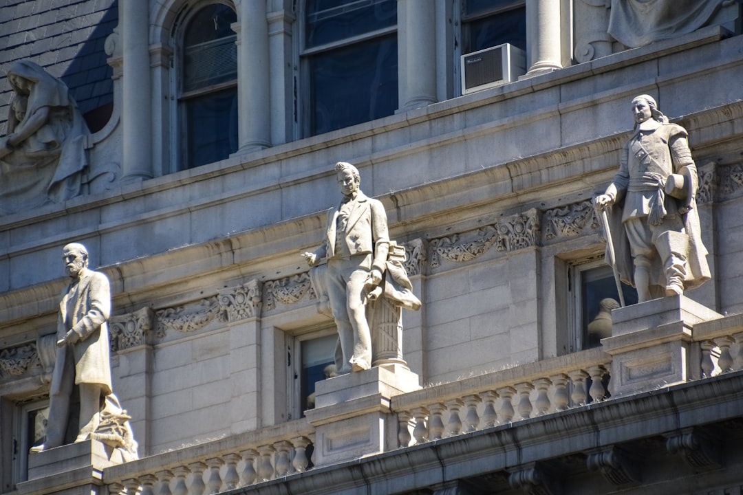 man in coat statue near white concrete building during daytime