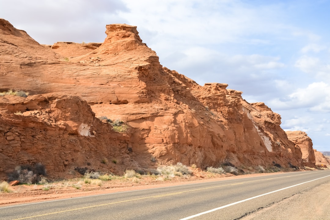 brown rock formation beside gray asphalt road during daytime