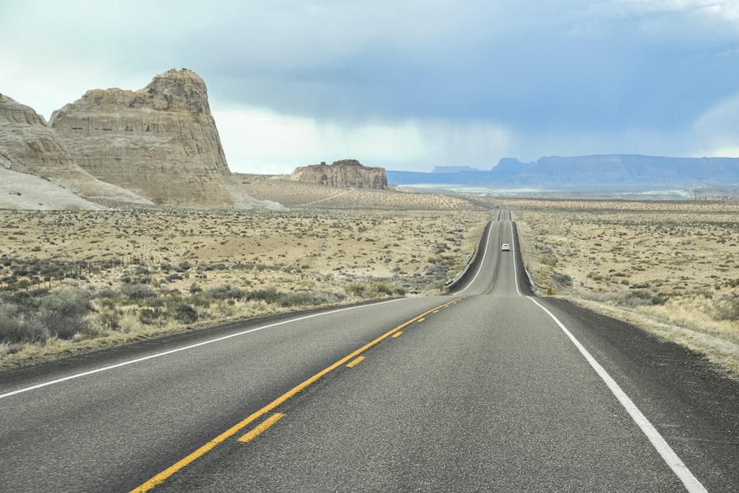 gray asphalt road near brown mountain under blue sky during daytime