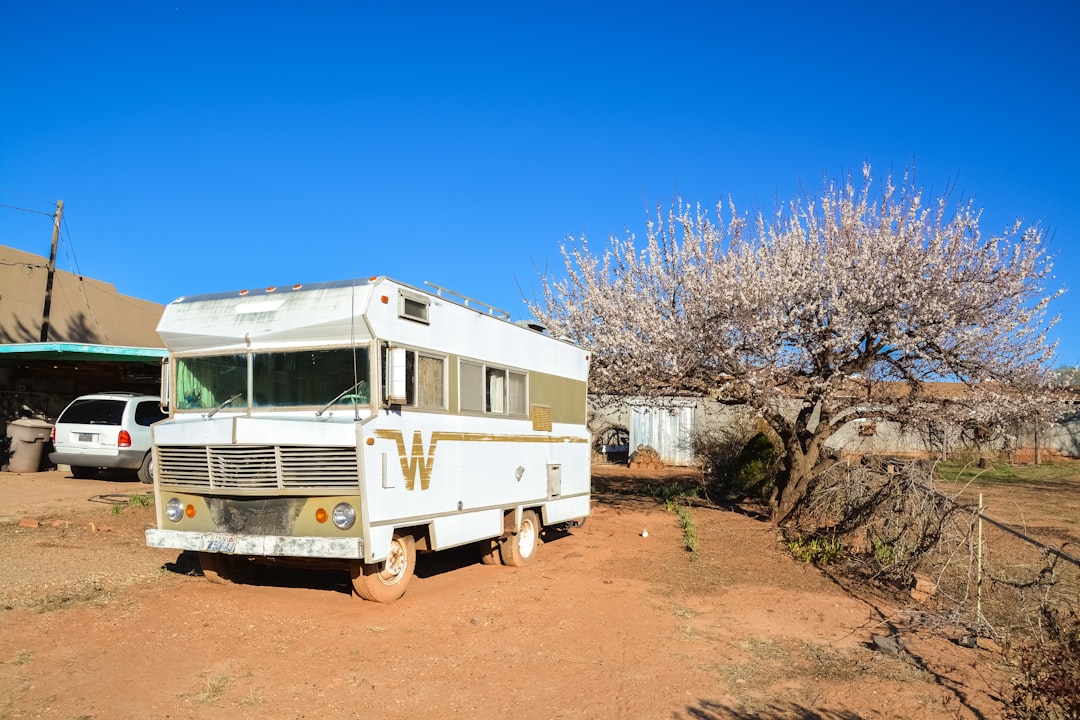 white and brown rv trailer on brown dirt road under blue sky during daytime