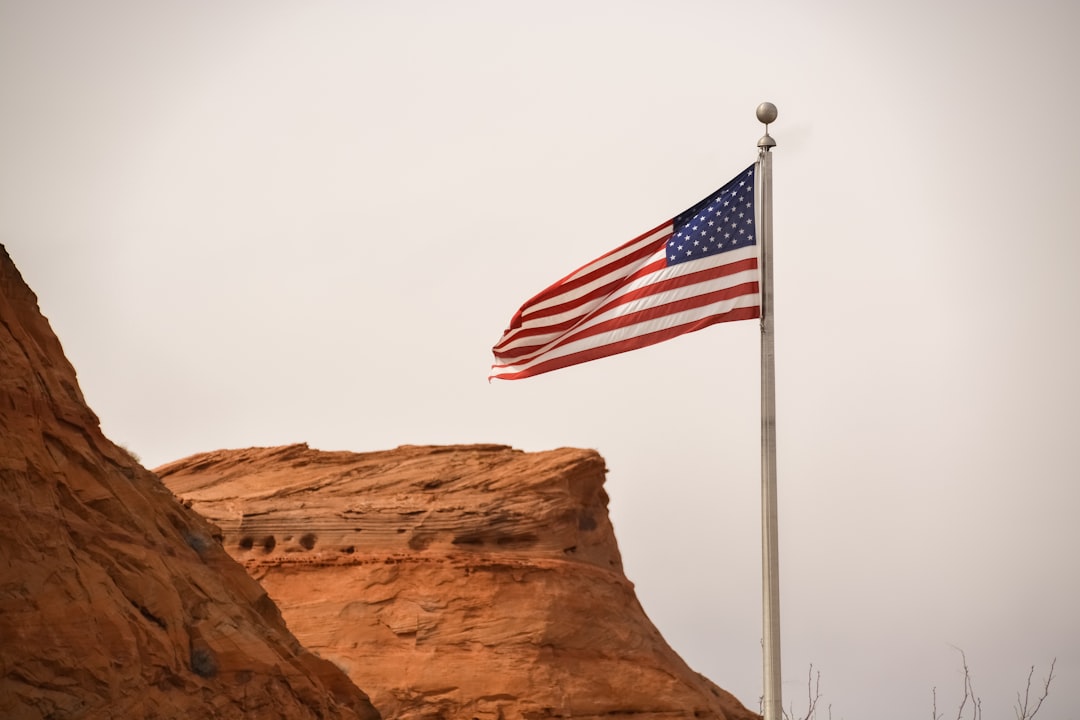 us a flag on brown rock formation under white sky during daytime