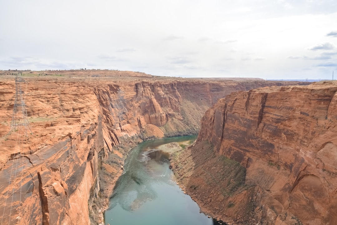 brown rock formation beside blue lake under white sky during daytime