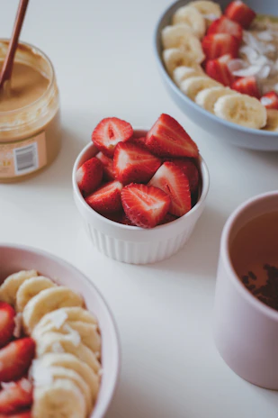 a bowl of sliced bananas and strawberries next to a bowl of sliced bananas