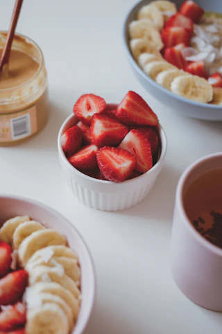 a bowl of sliced bananas and strawberries next to a bowl of sliced bananas