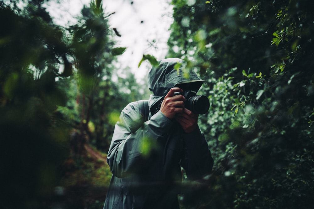 person in gray jacket holding black camera