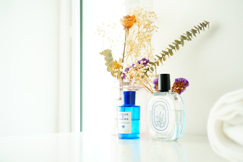 white and purple flowers in clear glass bottle