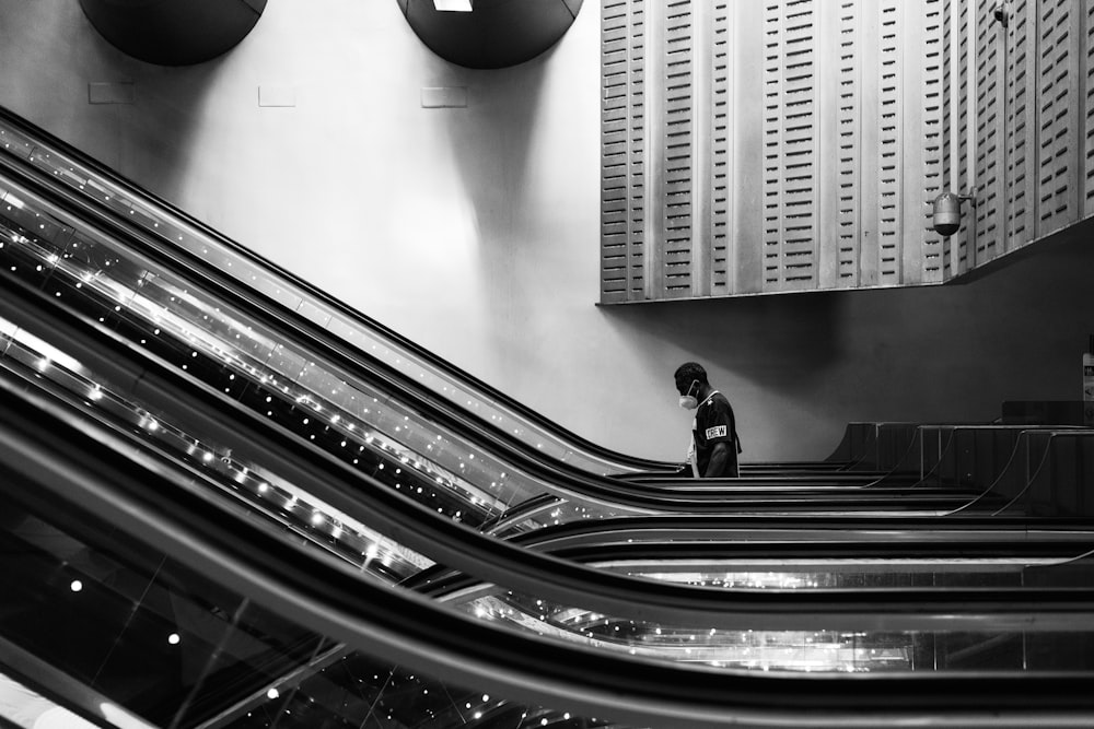 man in black jacket and pants standing on escalator