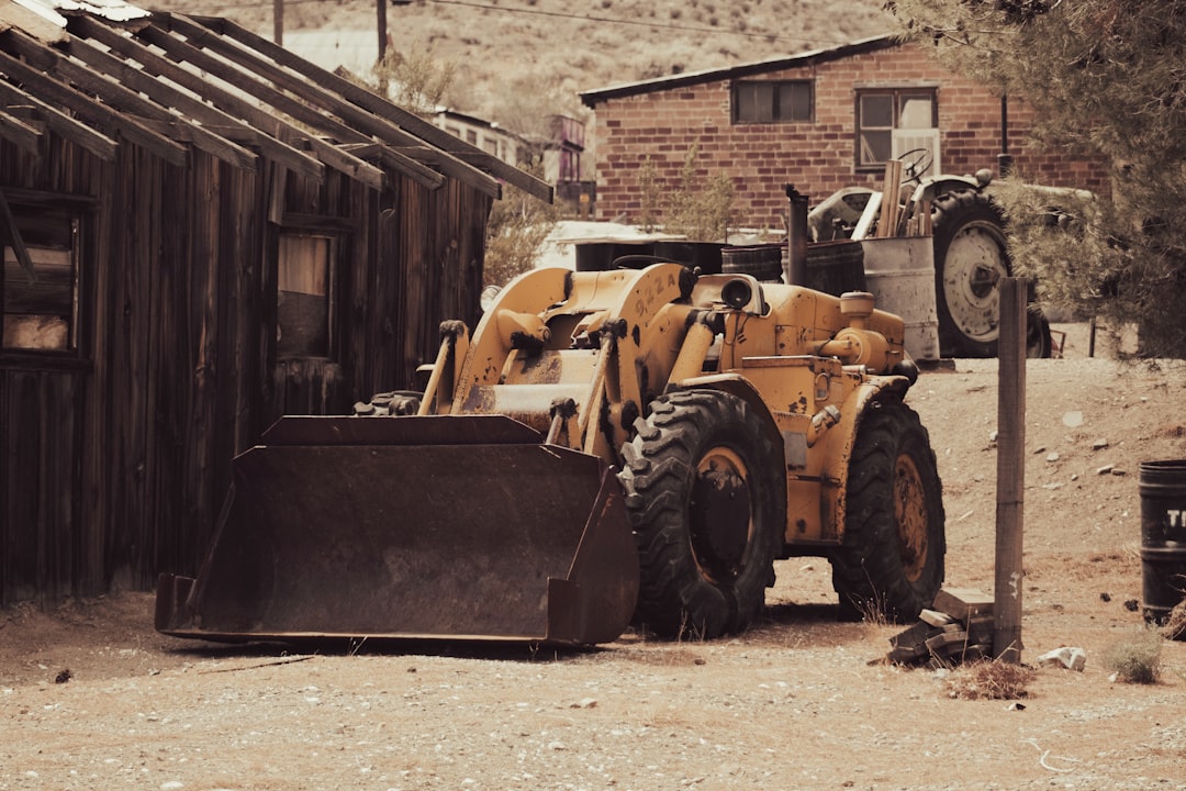 yellow front loader near brown wooden house