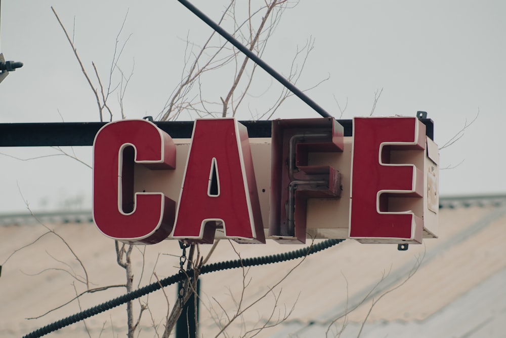 a red cafe sign hanging from the side of a building