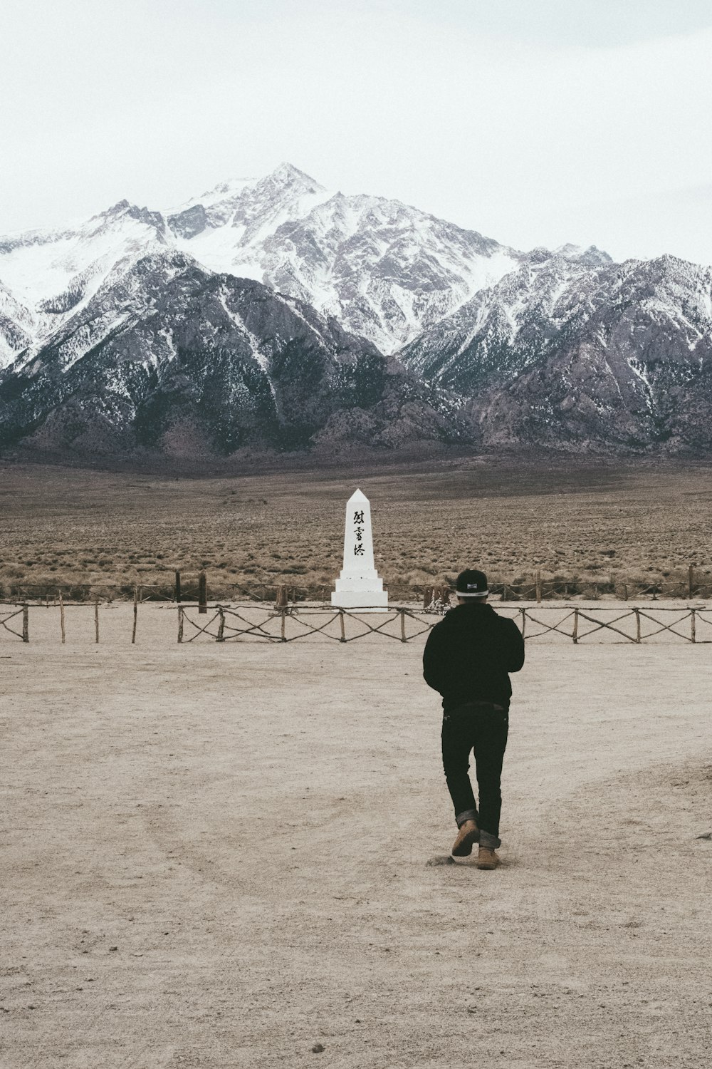 person in black jacket standing on brown field during daytime