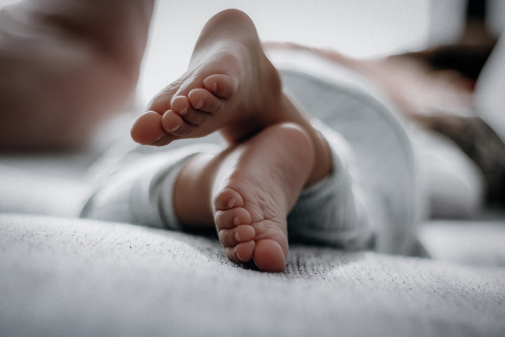 baby lying on white textile