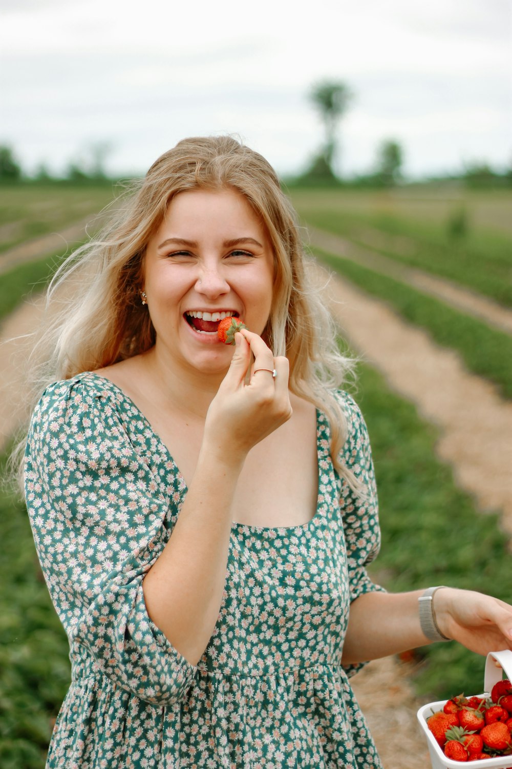 woman in white and black floral dress holding red lollipop