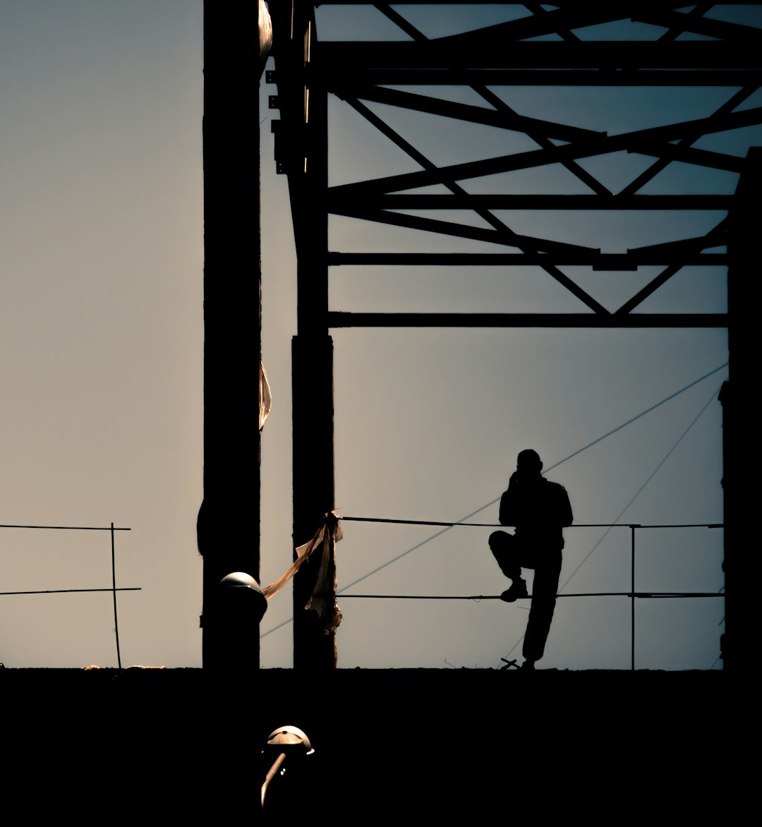 silhouette of man and woman standing on a metal frame ladder during daytime
