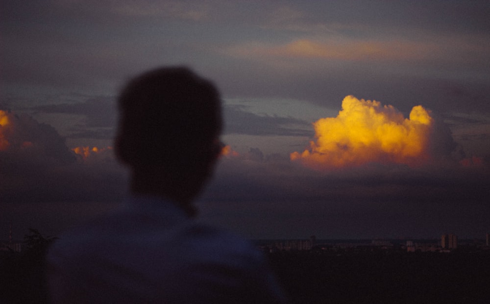 man in black hoodie standing under white clouds during daytime