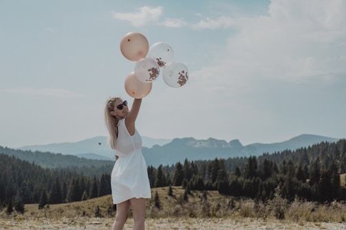 woman in white tank dress holding balloons