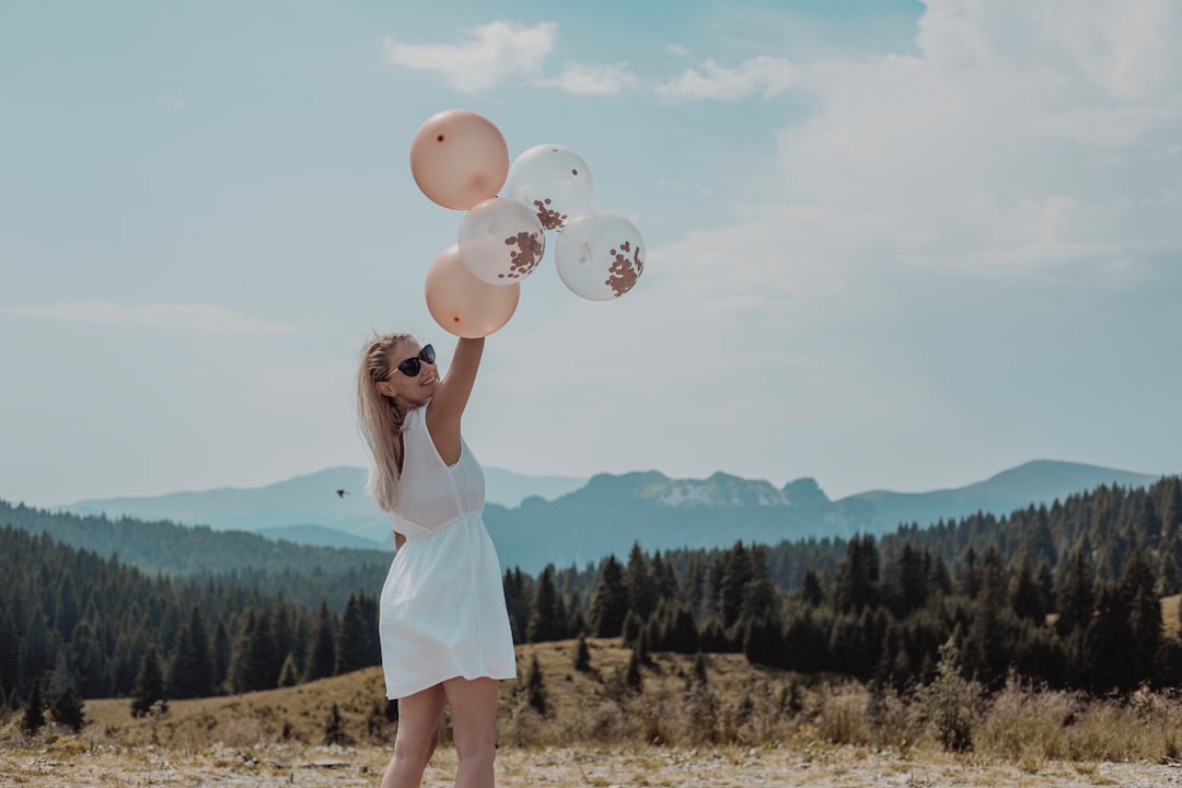 woman in white tank dress holding balloons