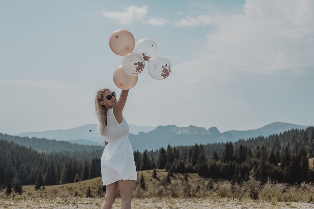 woman in white tank dress holding balloons