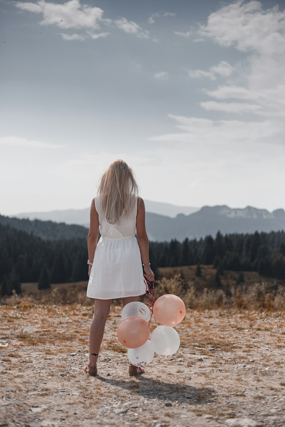 Frau in weißem Kleid hält Luftballons
