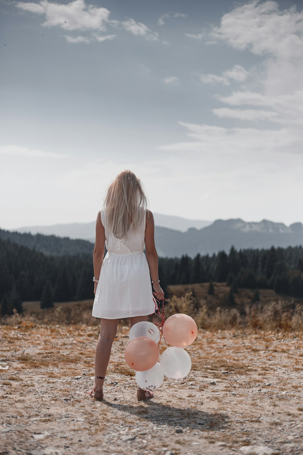 Femme en robe blanche tenant des ballons