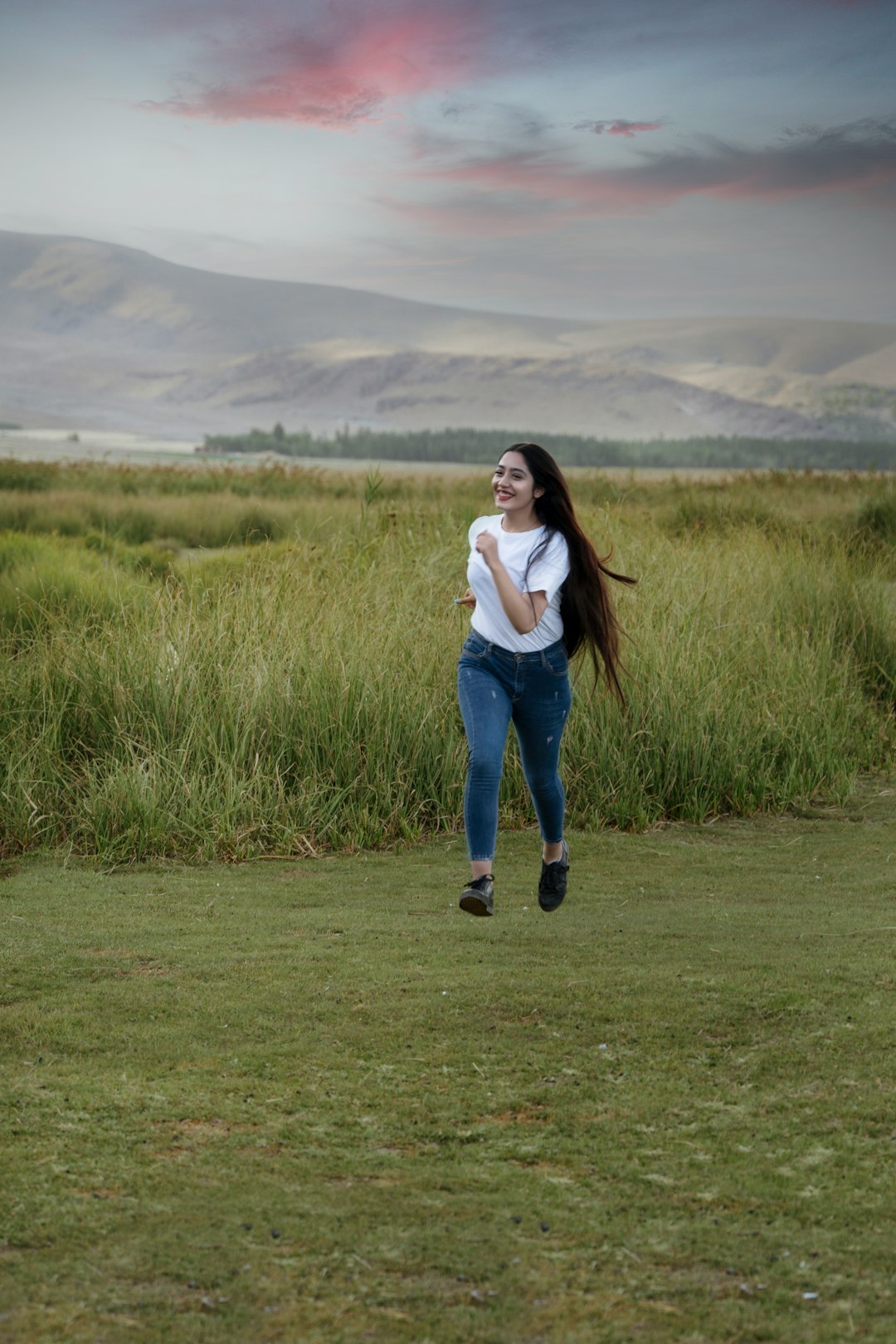 woman in white long sleeve shirt and blue denim jeans standing on green grass field during