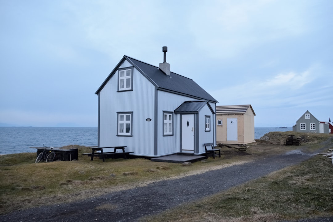 white wooden house near sea under white clouds during daytime