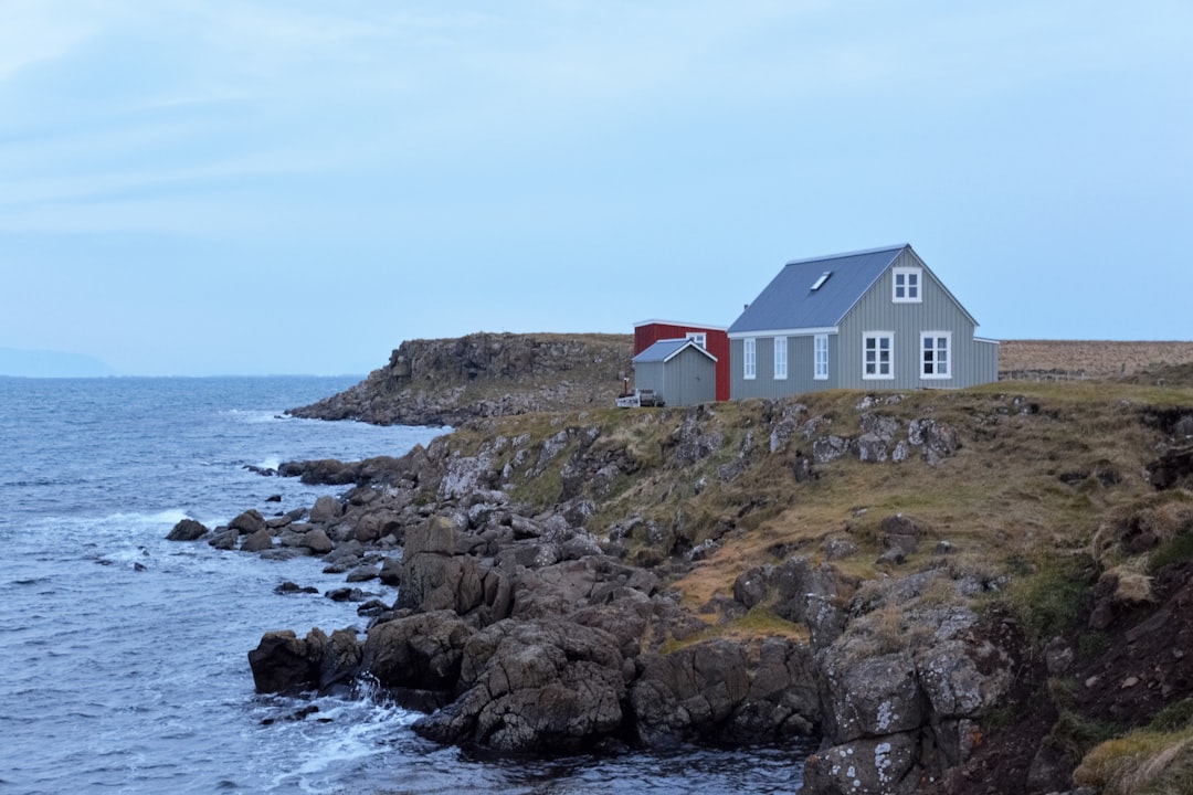 white and red house on brown rock formation beside body of water during daytime