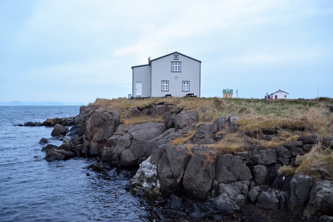 white house on brown rock formation beside sea during daytime