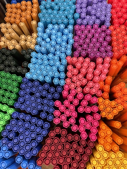 A close-up of colorful gel pens neatly arranged on a wooden desk.