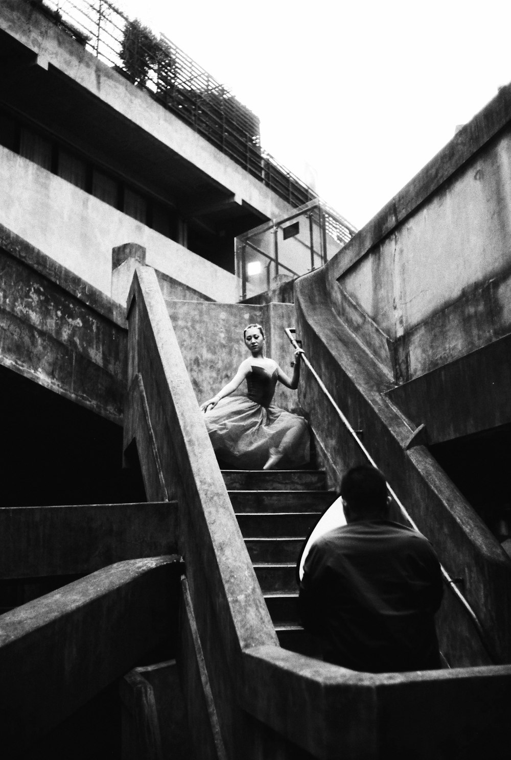 grayscale photo of man in black jacket standing on stairs