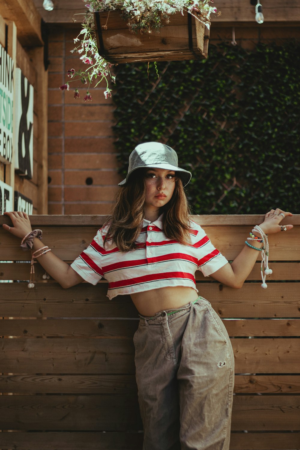 woman in white red and blue stripe shirt and brown denim jeans sitting on brown wooden