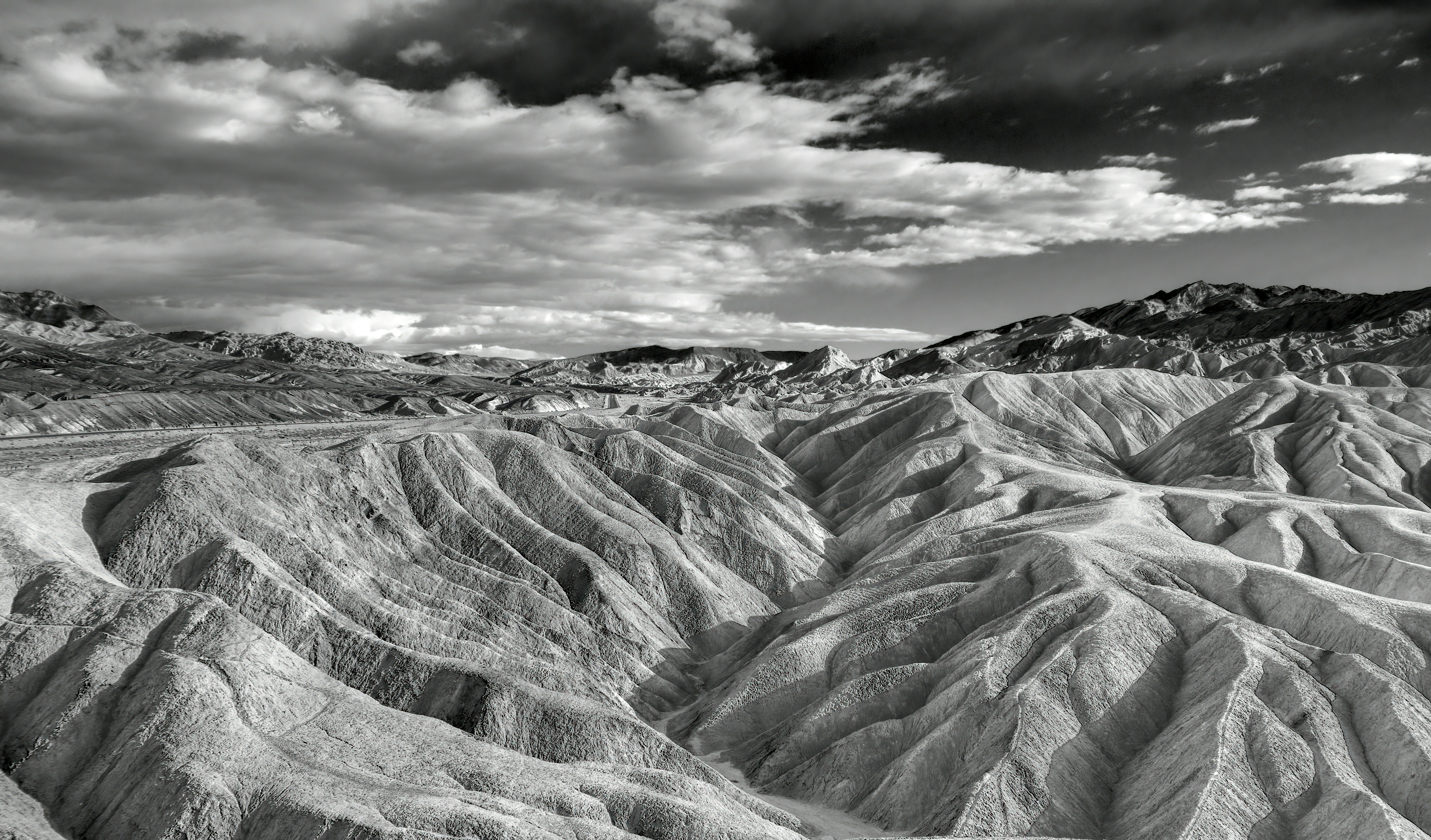 grayscale photo of rocky mountain under cloudy sky